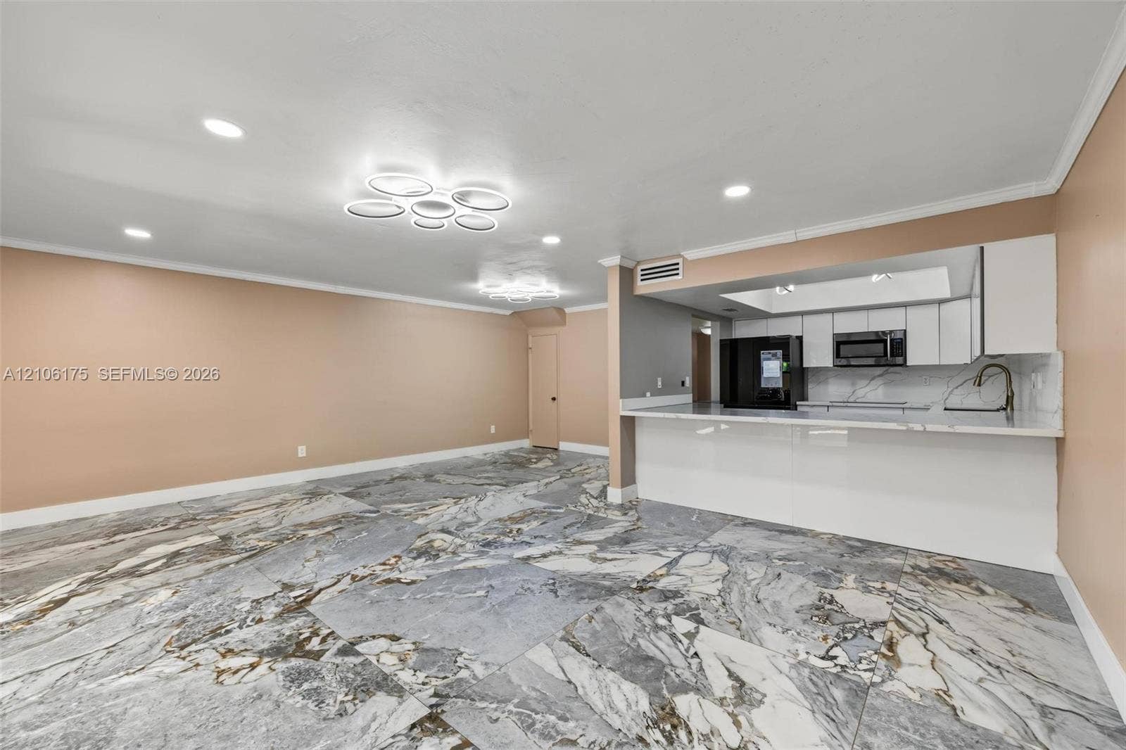6905 W 2nd Way, #1, Hialeah, Hialeah, FL 33014 Large format tile flooring with high-contrast veining, recessed lighting, sculptural LED light fixtures, white cabinetry, and a countertop with an integrated breakfast bar