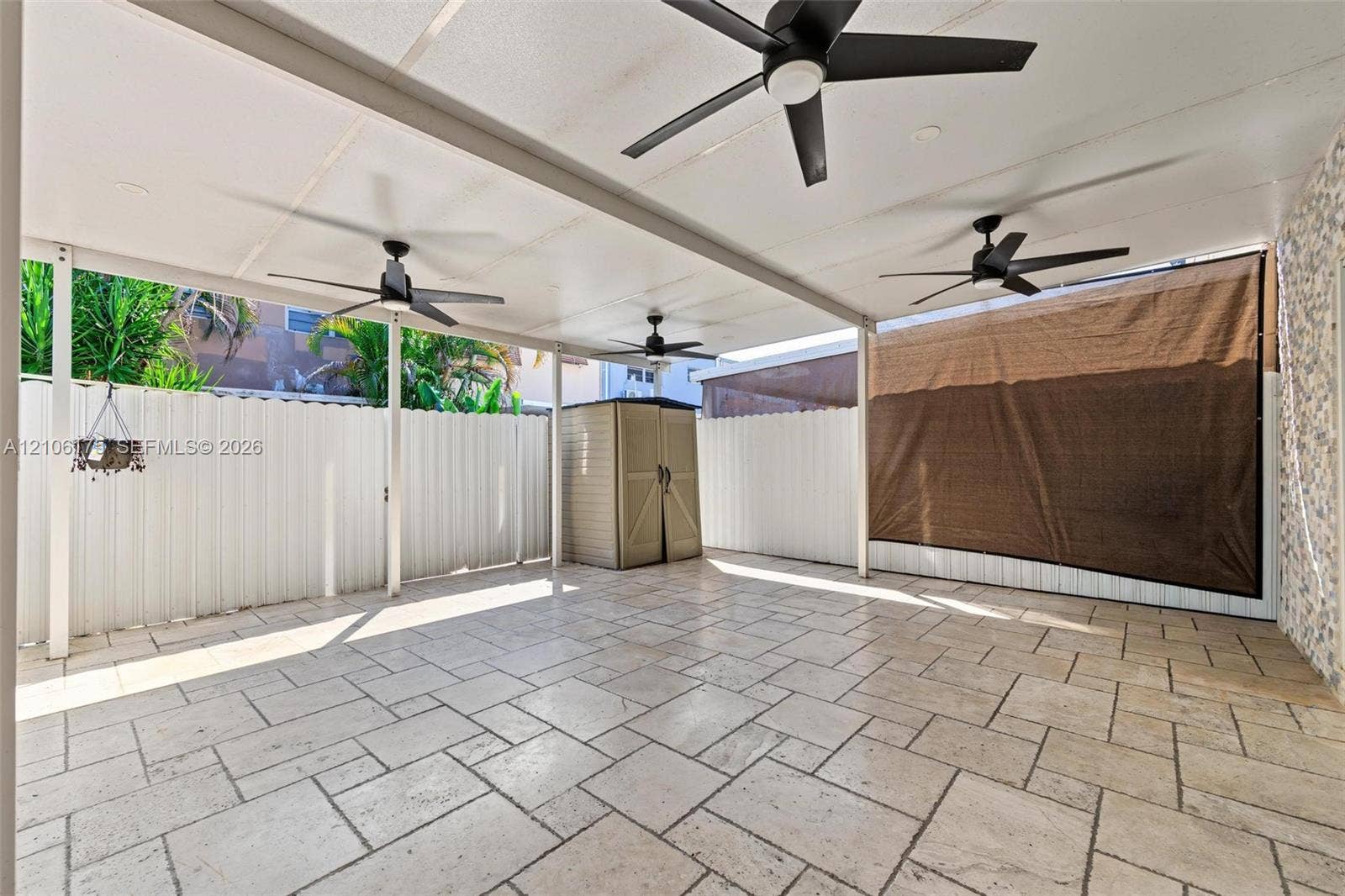 6905 W 2nd Way, #1, Hialeah, Hialeah, FL 33014 Covered patio featuring stone-tile flooring, three ceiling fans, and a white privacy fence