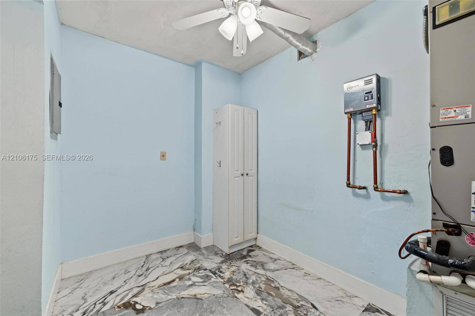 6905 W 2nd Way, #1, Hialeah, Hialeah, FL 33014 Utility area featuring large-format patterned stone-finish flooring, a ceiling-mounted fan with integrated light, a built-in vertical storage cabinet, and a wall-mounted water treatment system