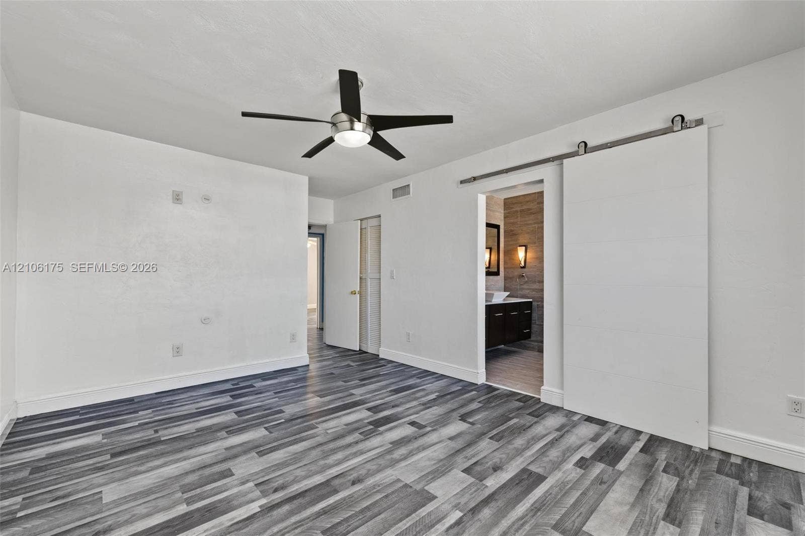 6905 W 2nd Way, #1, Hialeah, Hialeah, FL 33014 Wood-finish flooring, white sliding barn door, and a modern ceiling fan with integrated lighting