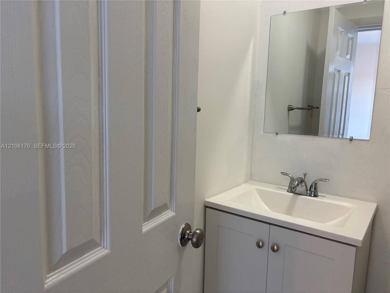 214 NW 46th Avenue, #214, Miami, Miami, FL 33126 Vanity cabinet with shaker-style doors, integrated sink basin, dual-handle faucet, and frameless wall-mounted mirror