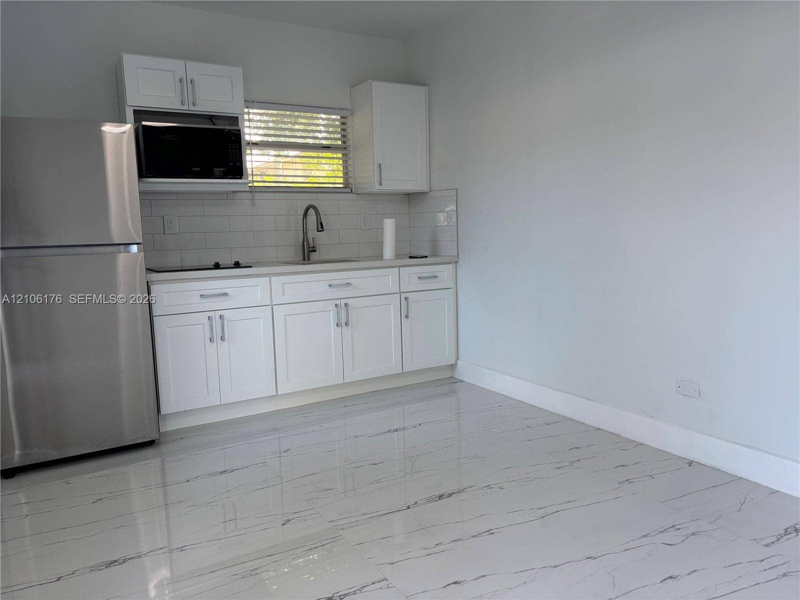 214 NW 46th Avenue, #214, Miami, Miami, FL 33126 Kitchen featuring white cabinetry, stainless steel refrigerator, white subway tile backsplash, arched faucet, and light-toned flooring with decorative veining