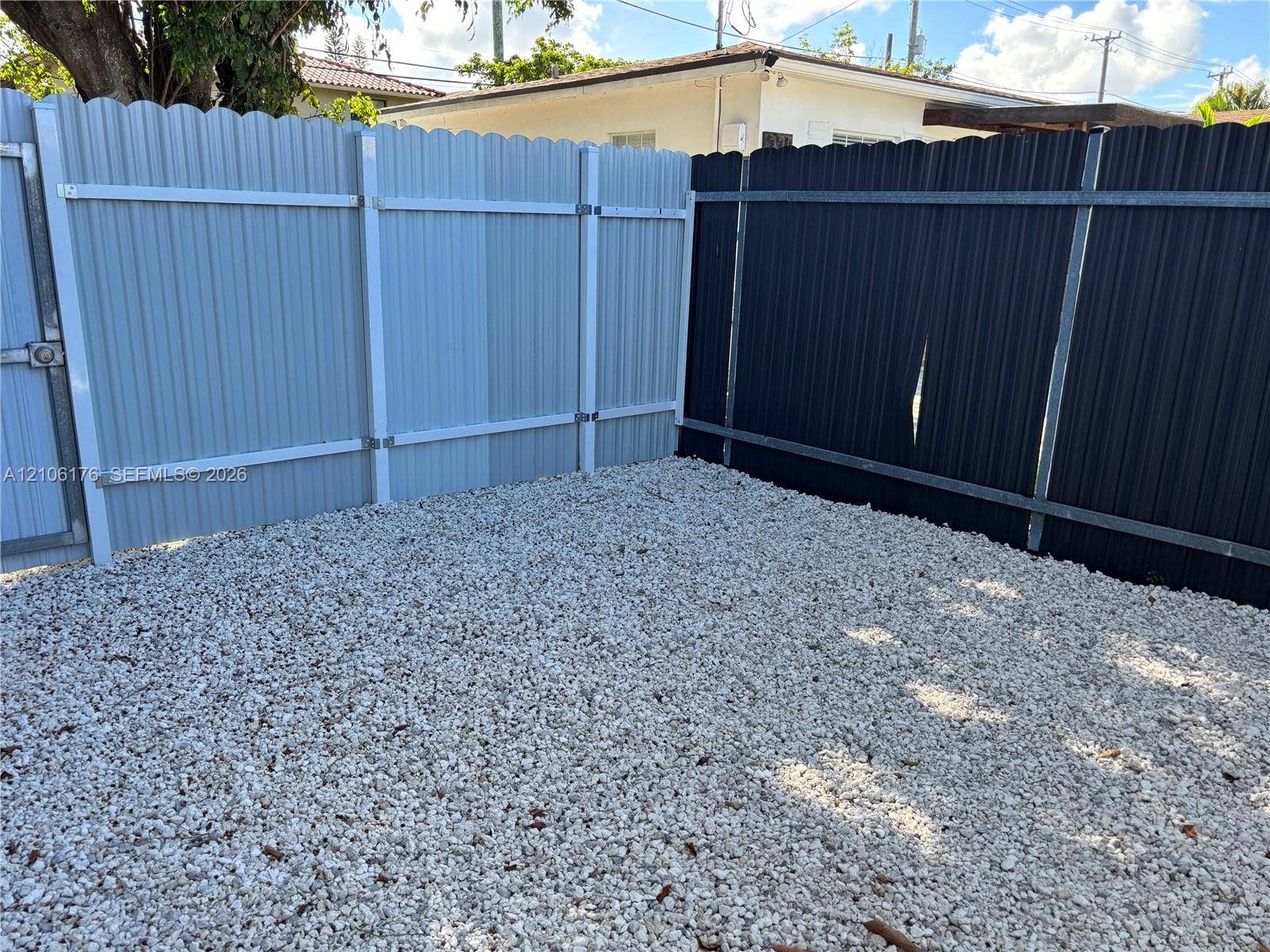 214 NW 46th Avenue, #214, Miami, Miami, FL 33126 Ground-level exterior area featuring low-maintenance gravel surfacing enclosed by corrugated metal fencing