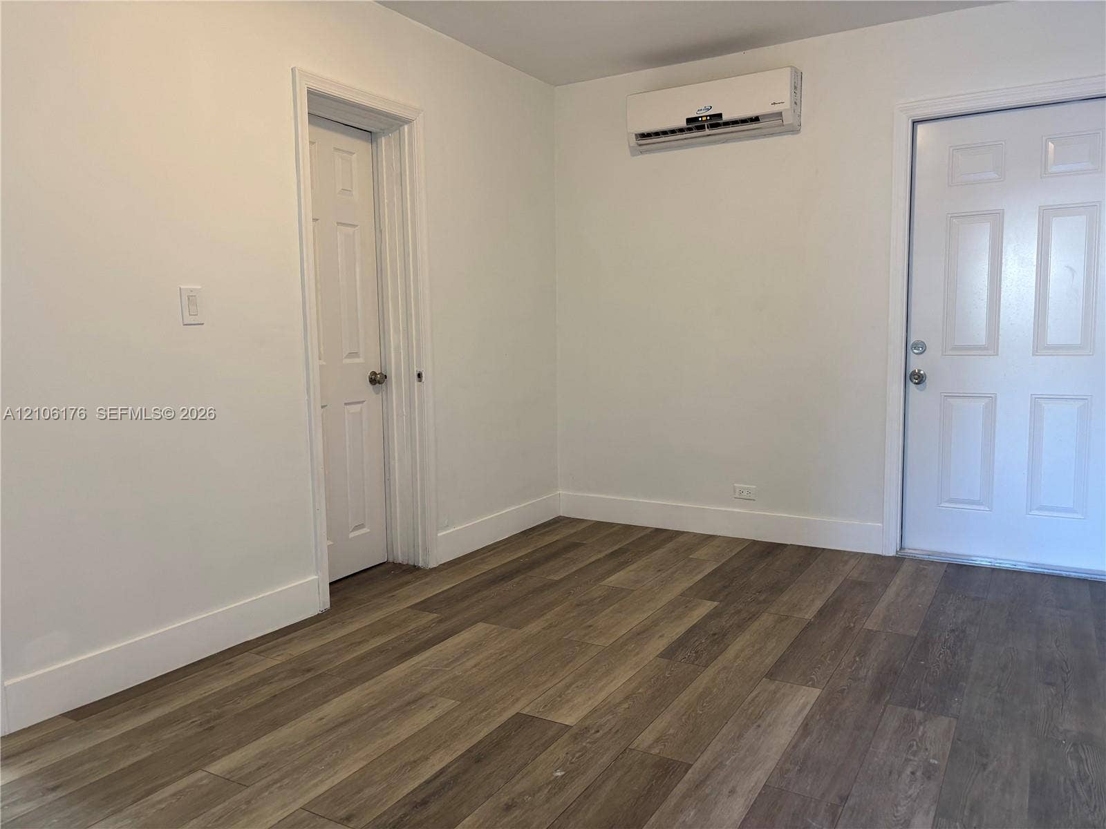 214 NW 46th Avenue, #214, Miami, Miami, FL 33126 Interior space featuring wood-finish flooring, a wall-mounted ductless mini-split HVAC unit, a six-panel door, and an exterior door with dual deadbolt hardware