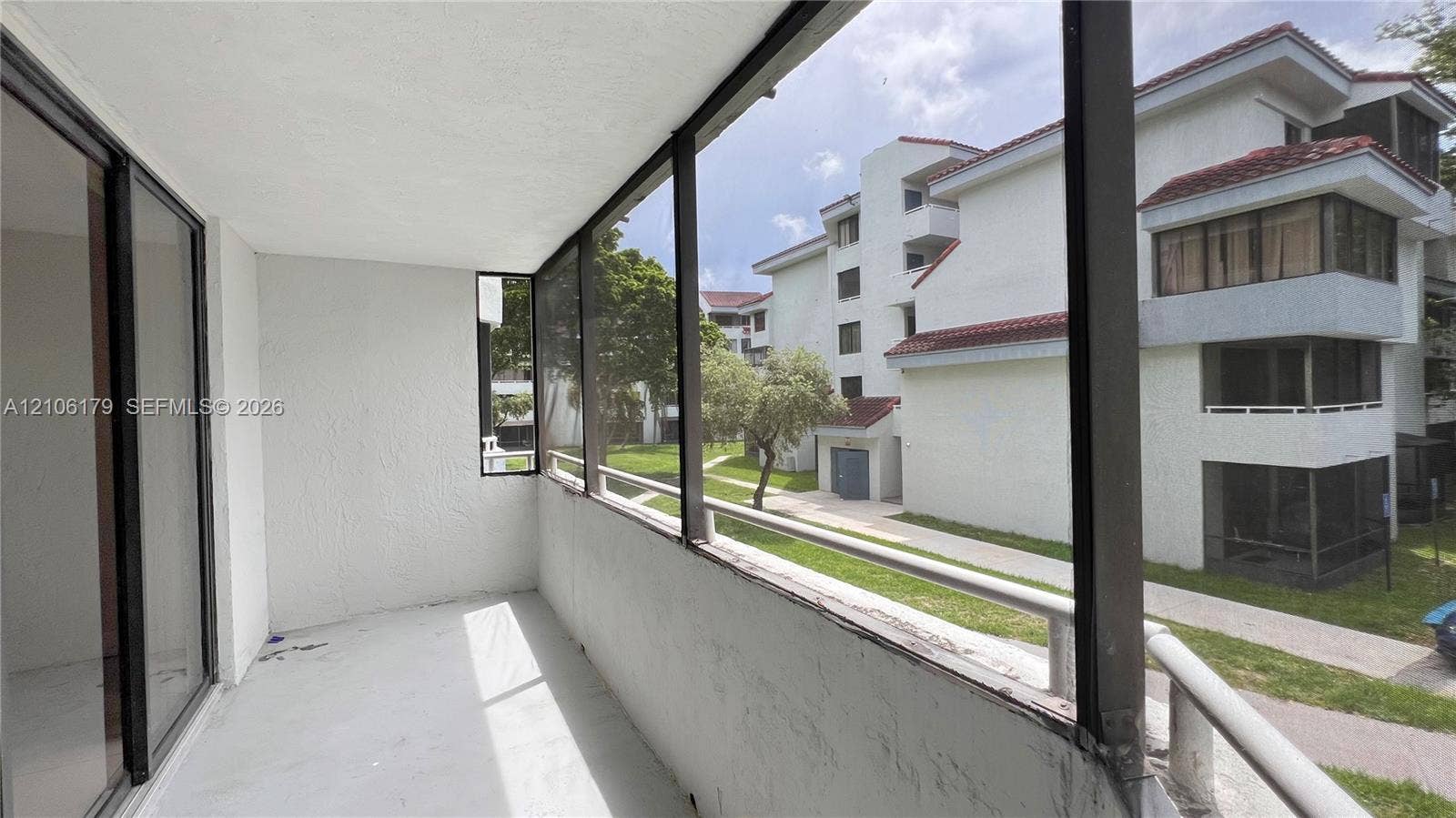 Screened-in balcony with metal framing, solid masonry wall, and white floor surfacing