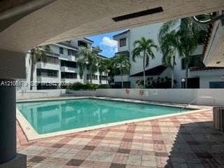 Swimming pool with a tile deck, perimeter wall, and surrounding palm trees