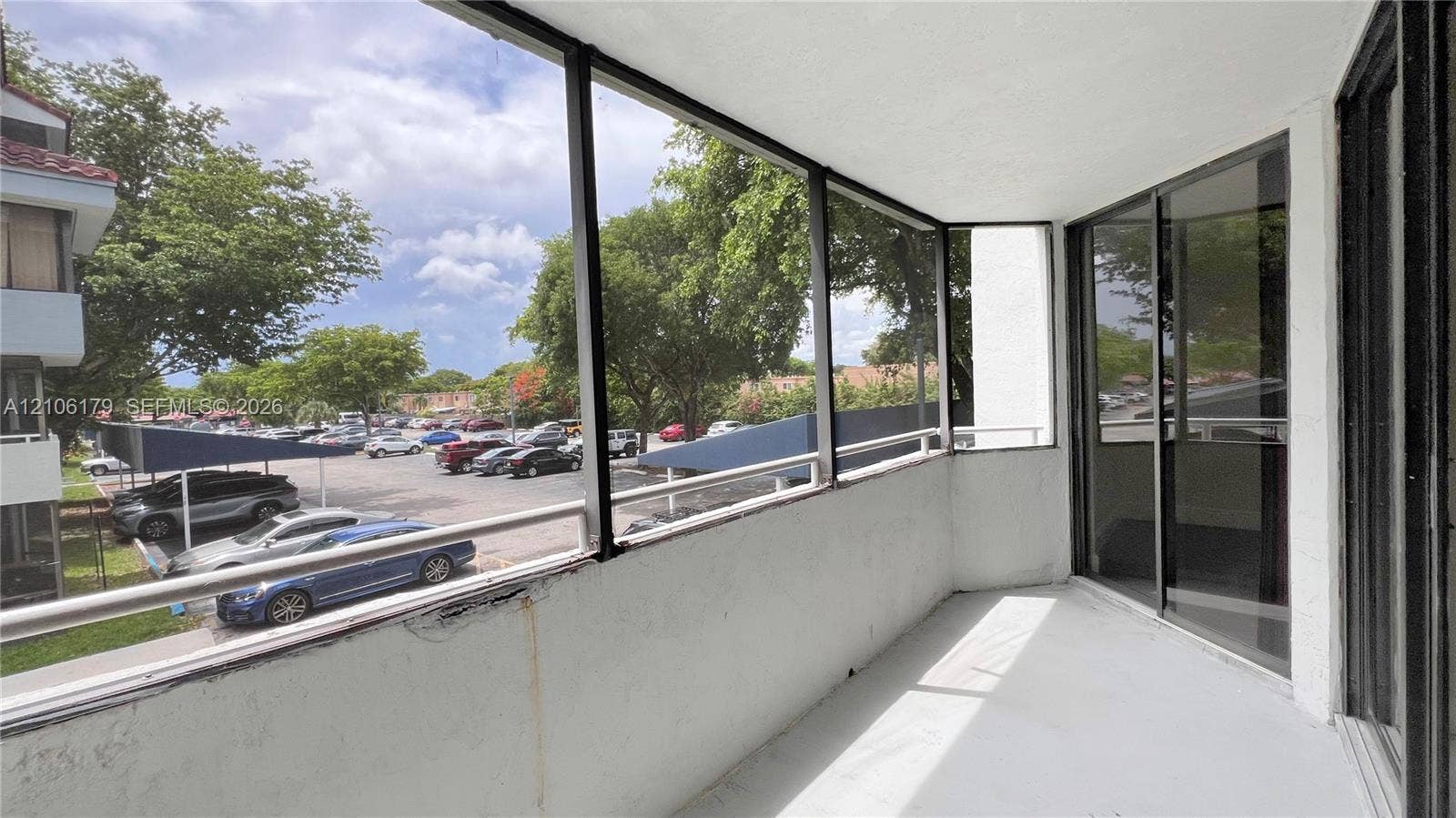 Screened-in balcony featuring a concrete floor, metal railings, and sliding glass door access