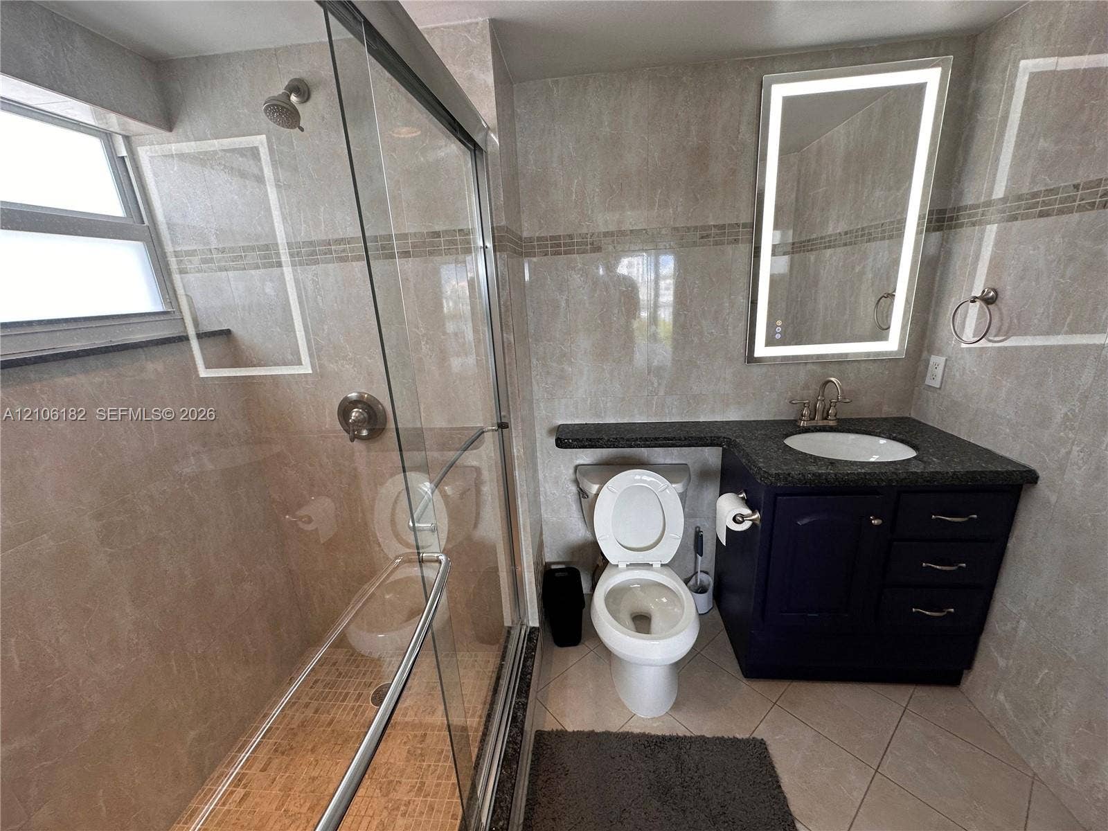 400 Golden Isles Drive, #40, Hallandale Beach, Hallandale Beach, FL 33009 Walk-in shower with glass enclosure, dark cabinetry vanity with integrated countertop, oval undermount sink, and illuminated mirror