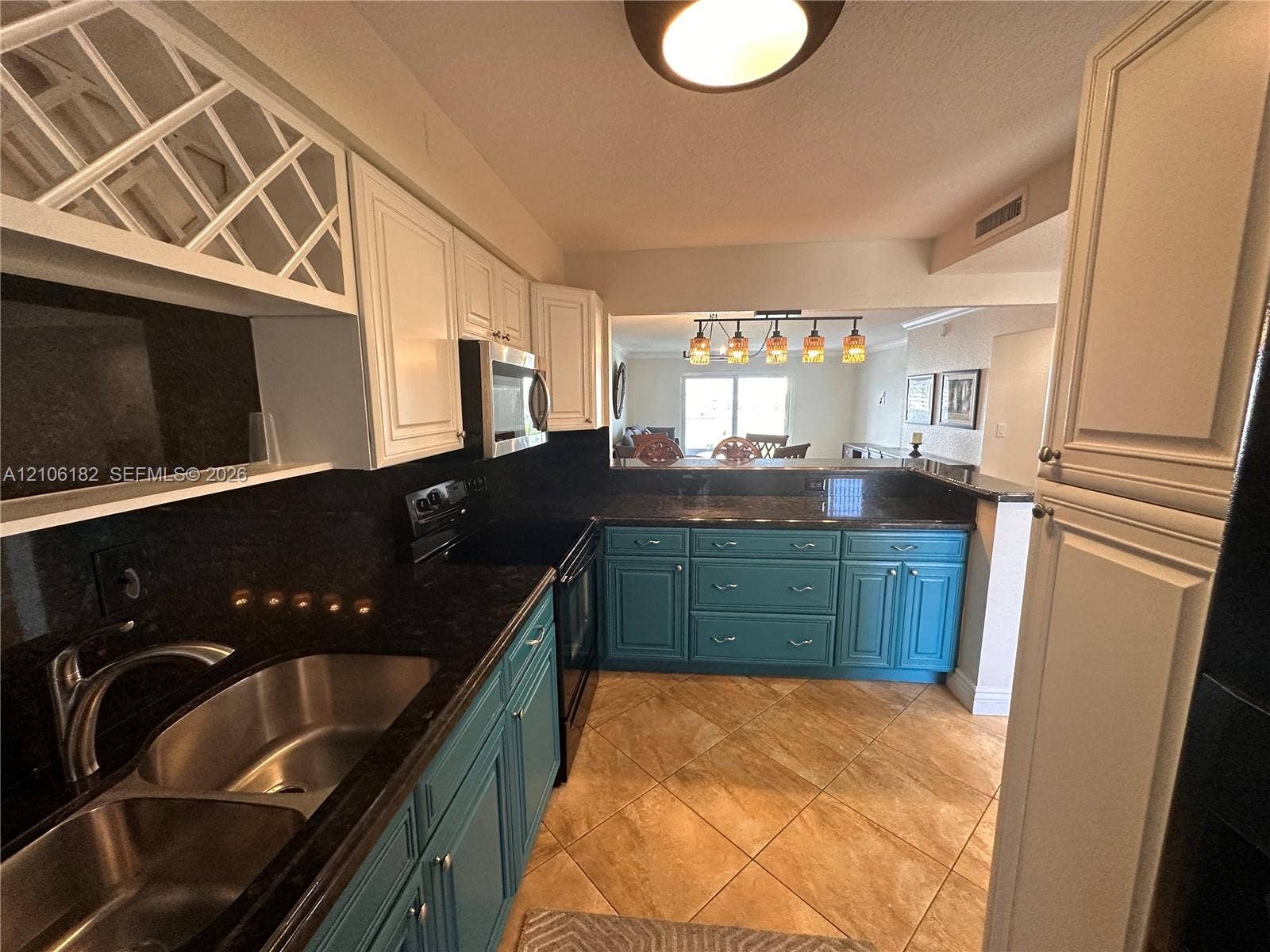 400 Golden Isles Drive, #40, Hallandale Beach, Hallandale Beach, FL 33009 Kitchen featuring two-tone cabinetry, dark stone countertops, diamond-pattern upper cabinet inserts, a dual-basin stainless steel sink, and diagonal-set tile flooring