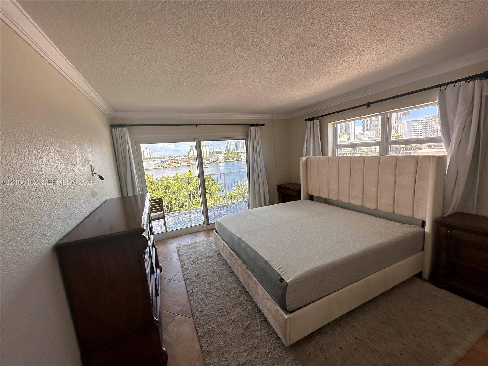 400 Golden Isles Drive, #40, Hallandale Beach, Hallandale Beach, FL 33009 Floor-to-ceiling sliding glass doors, neutral tile flooring, crown molding, and a private balcony featuring a water backdrop