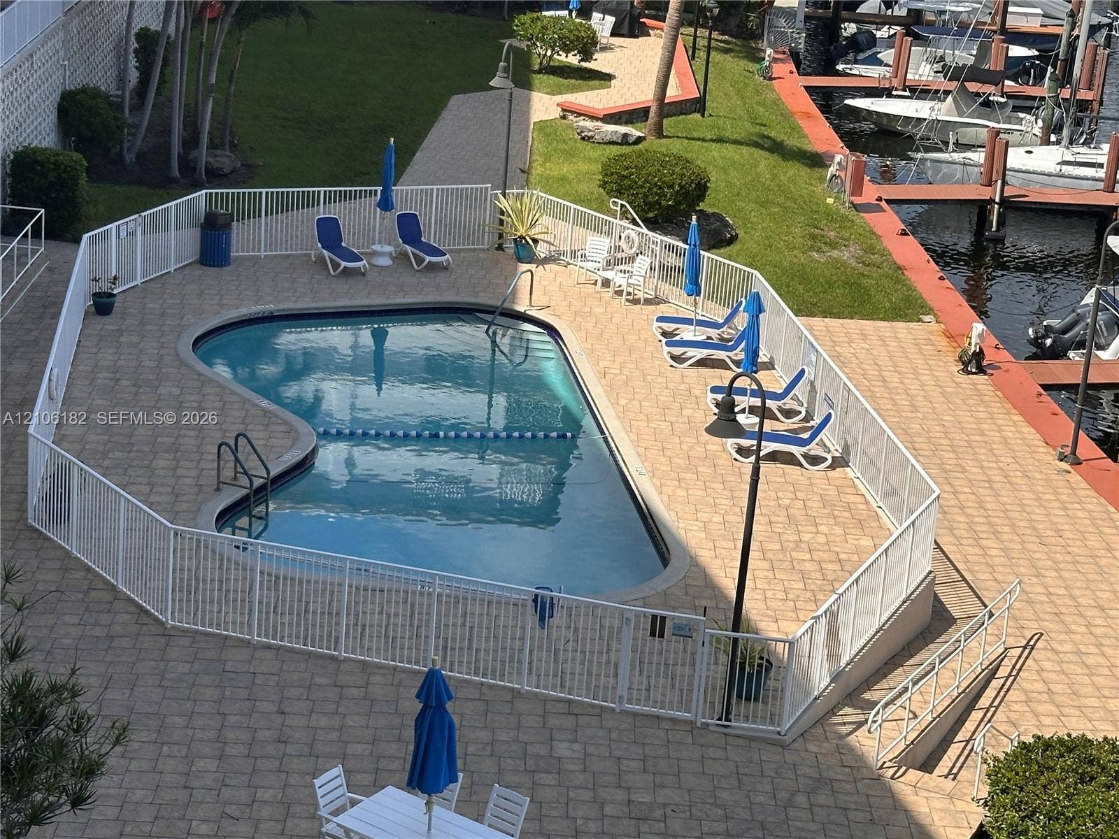 400 Golden Isles Drive, #40, Hallandale Beach, Hallandale Beach, FL 33009 Inground swimming pool with paver decking and white perimeter fencing, situated on a waterfront lot with dock access