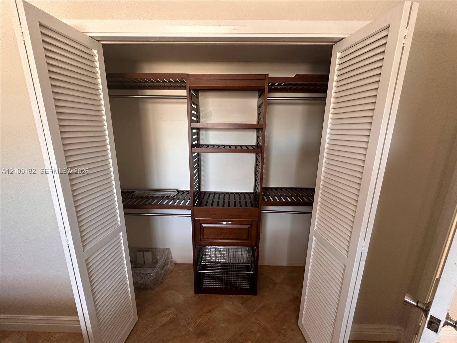400 Golden Isles Drive, #40, Hallandale Beach, Hallandale Beach, FL 33009 Closet featuring white louvered bifold doors, built-in wooden shelving, integrated storage drawers, pull-out wire organizing baskets, and tile flooring