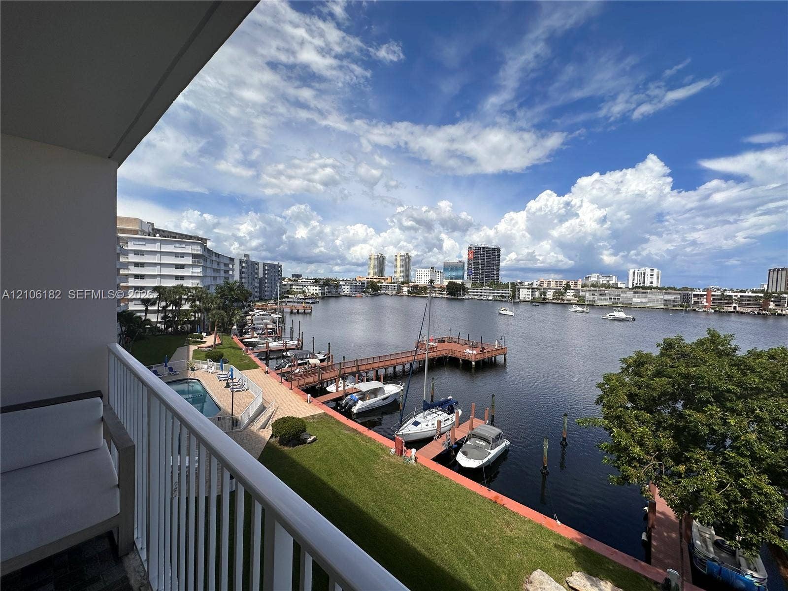 400 Golden Isles Drive, #40, Hallandale Beach, Hallandale Beach, FL 33009 Private balcony with a metal railing overlooking the waterway, featuring a dock, boat slips, and an inground swimming pool