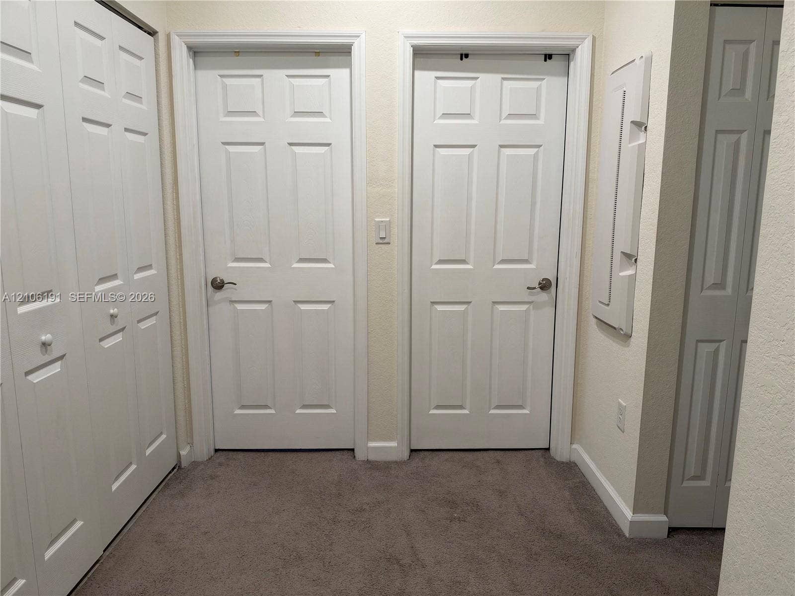 3402 W 105th Street, Hialeah, FL 33018 Interior space featuring neutral wall-to-wall carpeting, multiple six-panel interior doors, and built-in closet storage with bi-fold doors