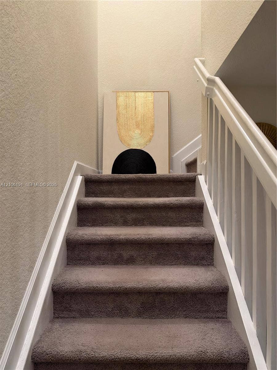 3402 W 105th Street, Hialeah, FL 33018 Staircase featuring wall-to-wall carpeting, white painted wooden balusters, and a matching handrail