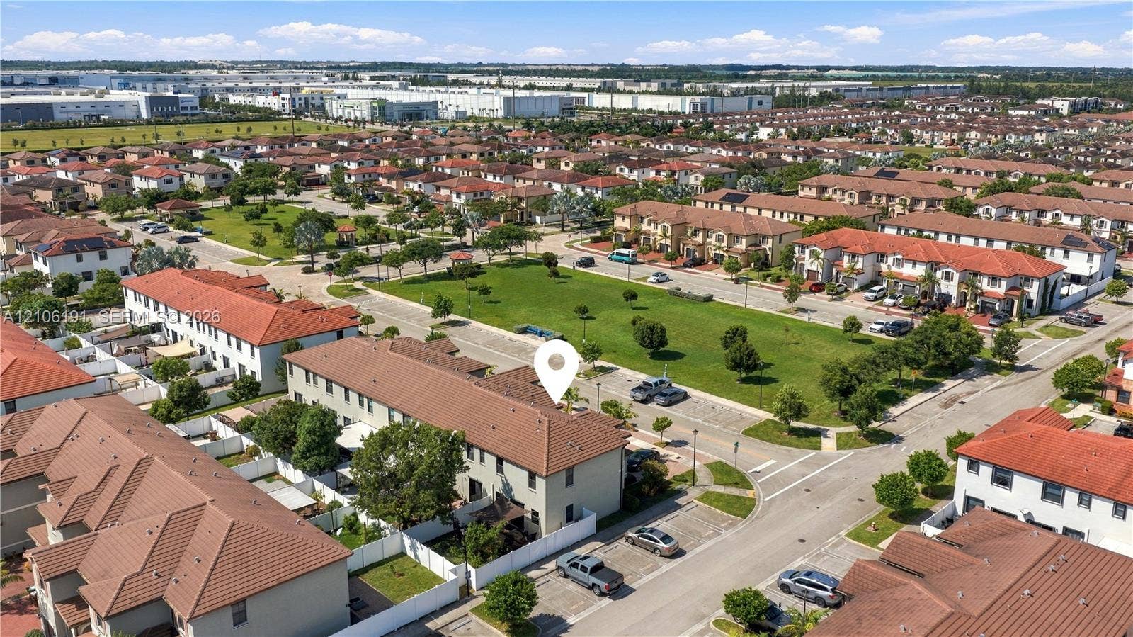 3402 W 105th Street, Hialeah, FL 33018 Aerial perspective of a multi-story residence with a clay tile roof, situated in a community featuring expansive green space and dedicated parking areas
