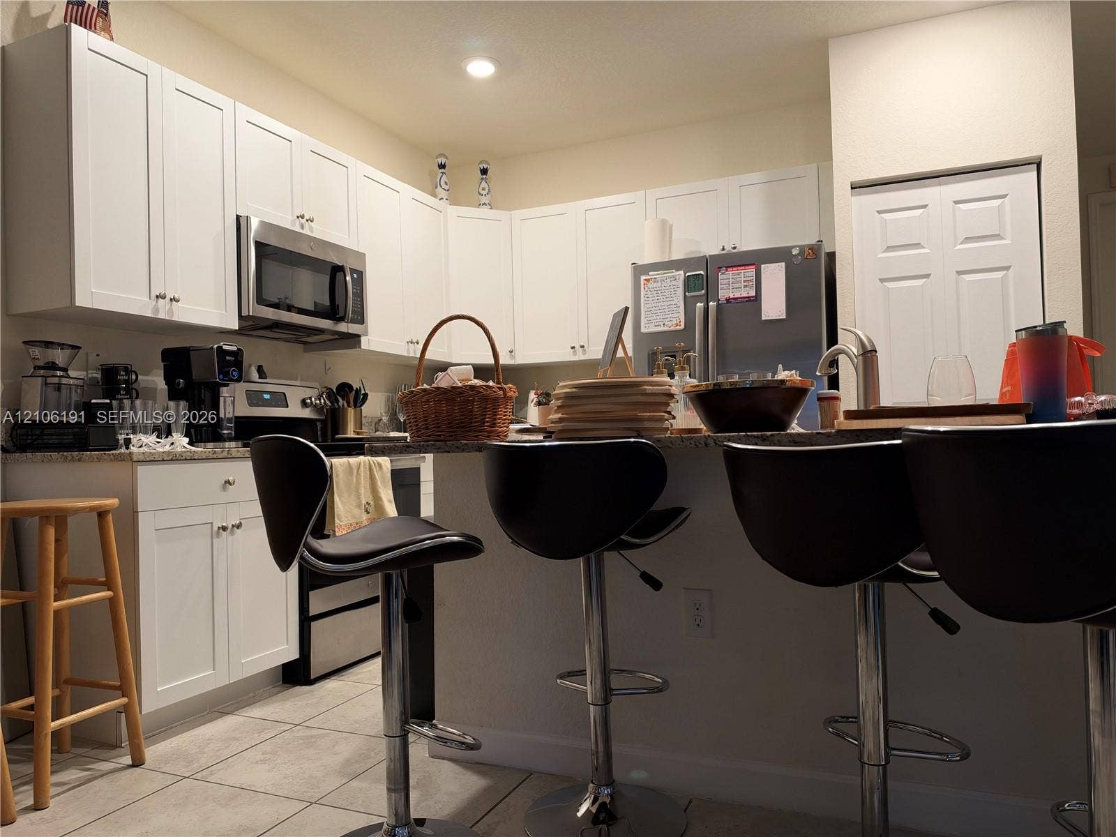 3402 W 105th Street, Hialeah, FL 33018 Kitchen featuring white shaker-style cabinetry, stone countertops, stainless steel appliances, and a breakfast bar with a chrome faucet