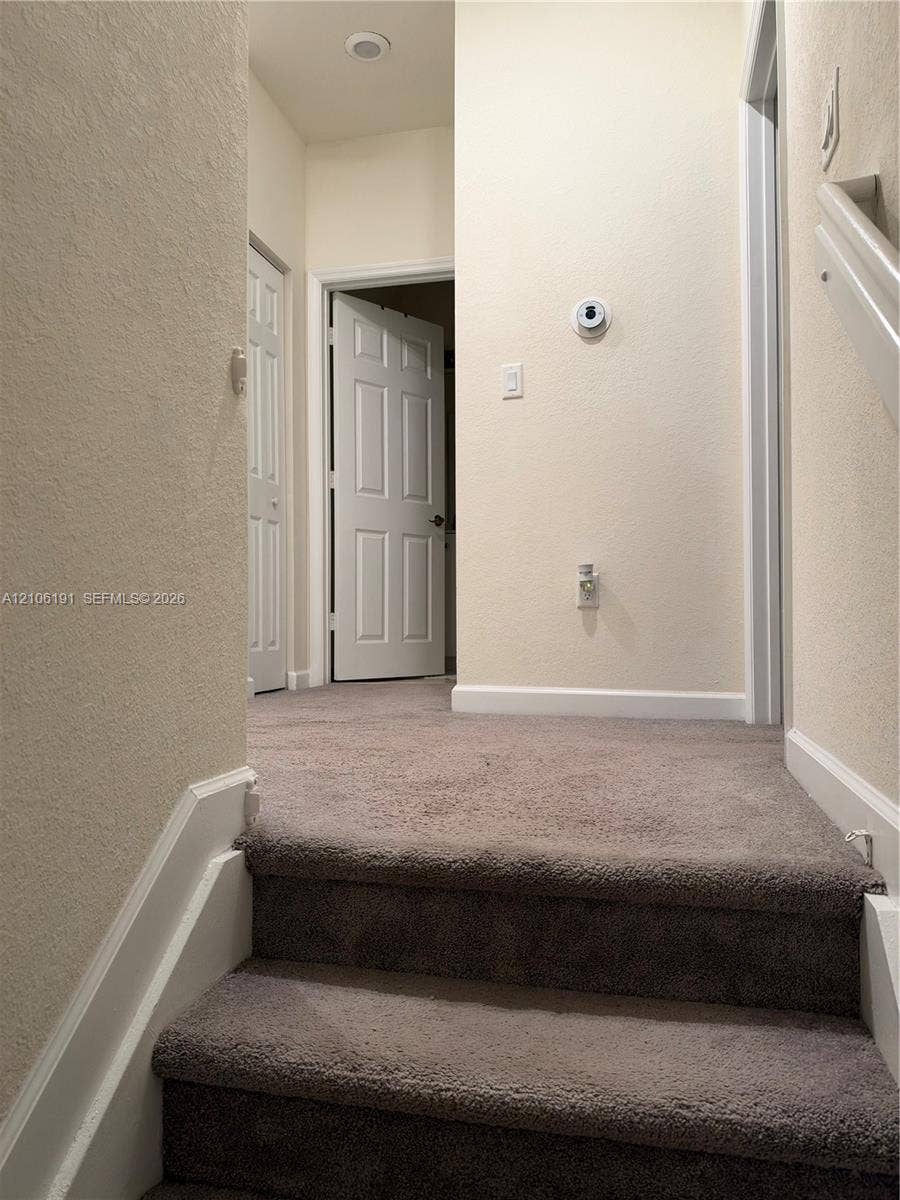 3402 W 105th Street, Hialeah, FL 33018 Neutral carpeted flooring, white six-panel interior doors, and wall-mounted digital thermostat