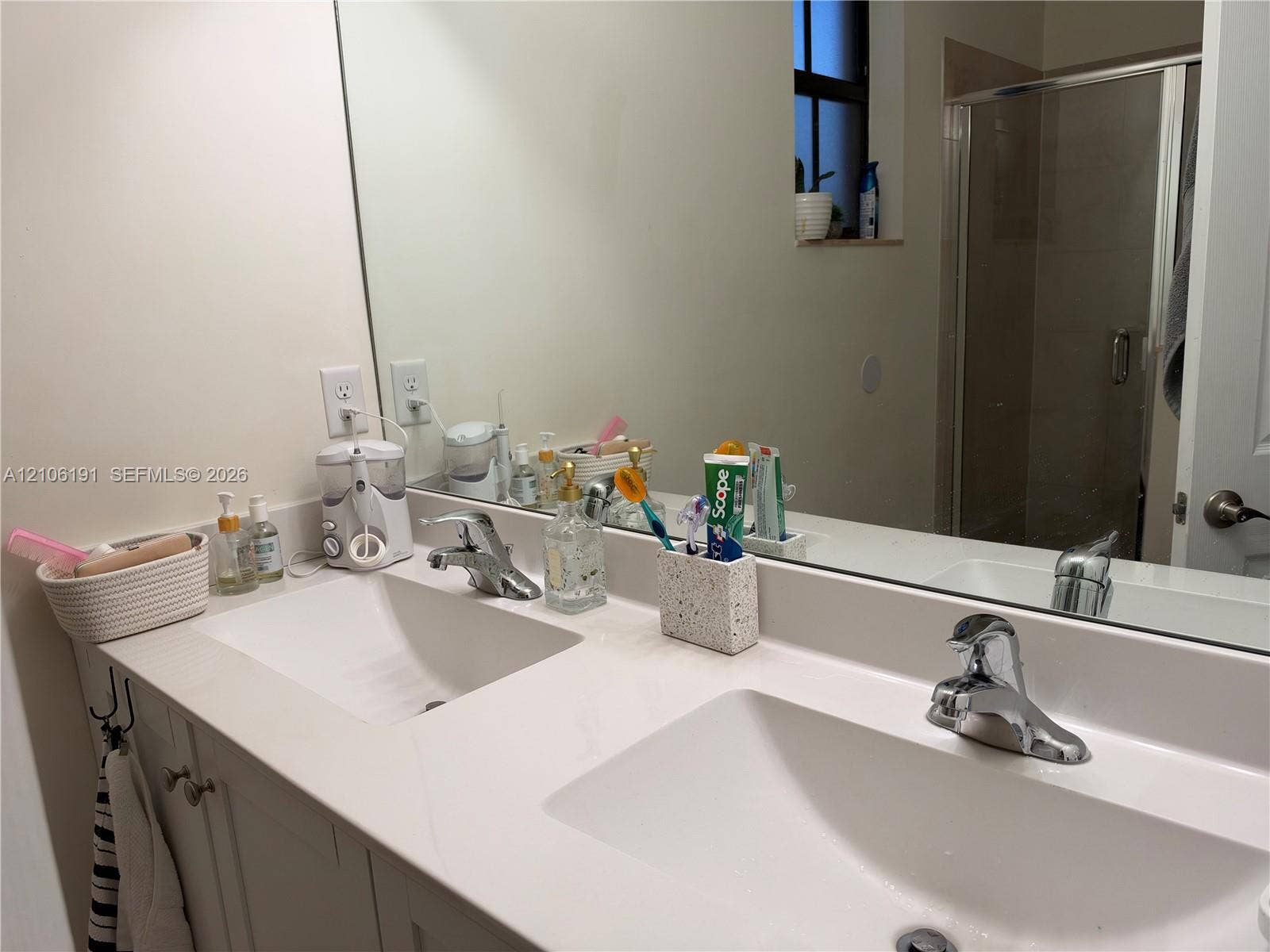 3402 W 105th Street, Hialeah, FL 33018 Dual-sink vanity with white countertop, integrated basin sinks, chrome faucets, and large wall-mounted mirror