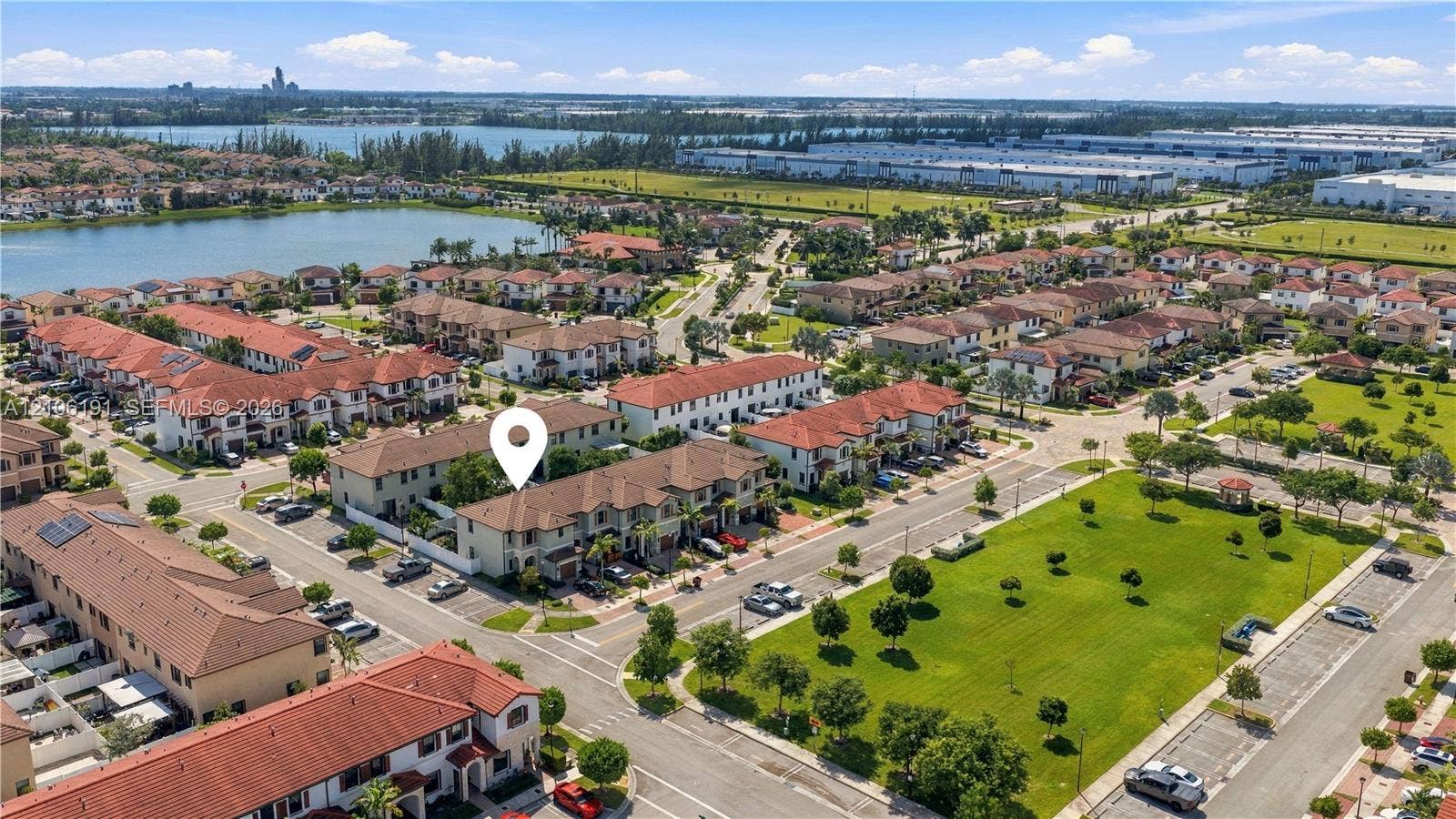 3402 W 105th Street, Hialeah, FL 33018 Aerial perspective of residential community featuring Mediterranean-style architecture with terracotta roof tiles, paved street grid, and proximity to a lake and landscaped green spaces