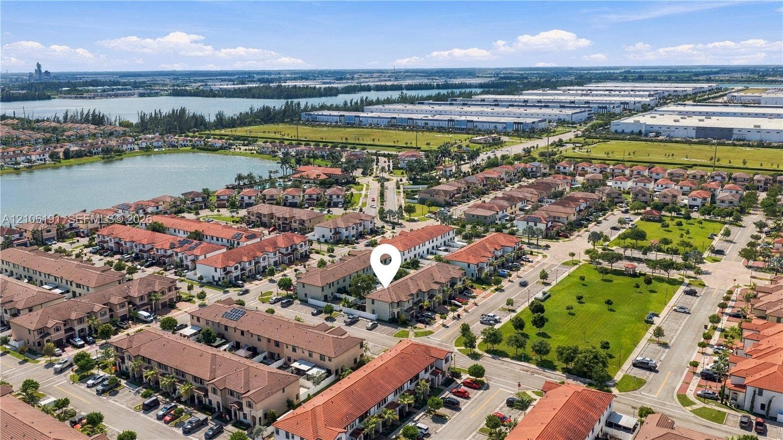 3402 W 105th Street, Hialeah, FL 33018 Aerial perspective of residential community featuring terra-cotta tile roofing, stucco exterior siding, paved street access, and water features