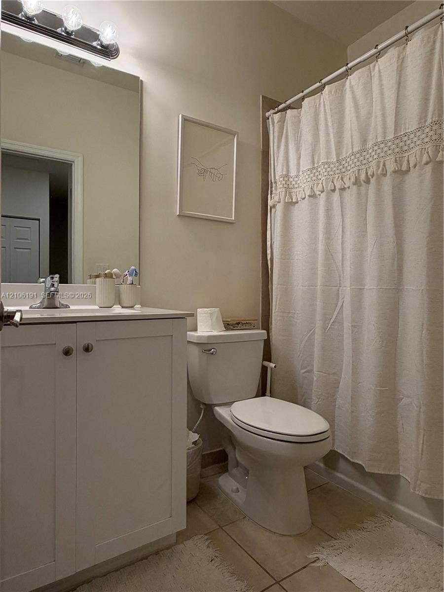 3402 W 105th Street, Hialeah, FL 33018 Bathroom featuring a white shaker-style vanity cabinet, large wall-mounted mirror, polished chrome faucet, and integrated lighting fixture above the mirror