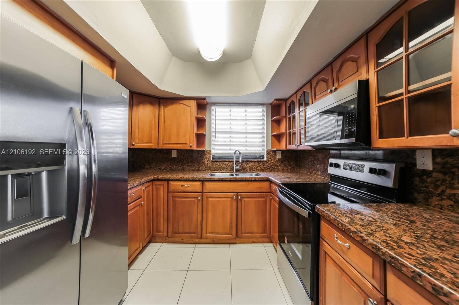 19100 NW 12th Avenue, Miami Gardens, Miami Gardens, FL 33169 Kitchen featuring warm-tone cabinetry, stone-finish countertops, stainless steel appliances, tile flooring, and a tray ceiling with recessed lighting