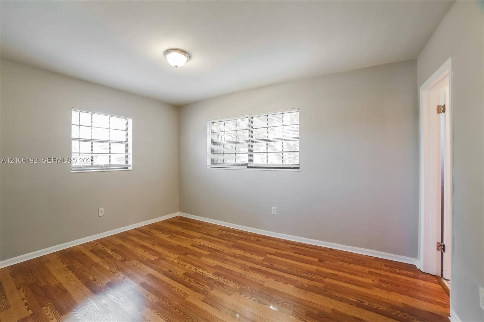 19100 NW 12th Avenue, Miami Gardens, Miami Gardens, FL 33169 Room featuring wood-finish flooring, neutral wall paint, multi-pane windows, and a flush-mount ceiling light fixture