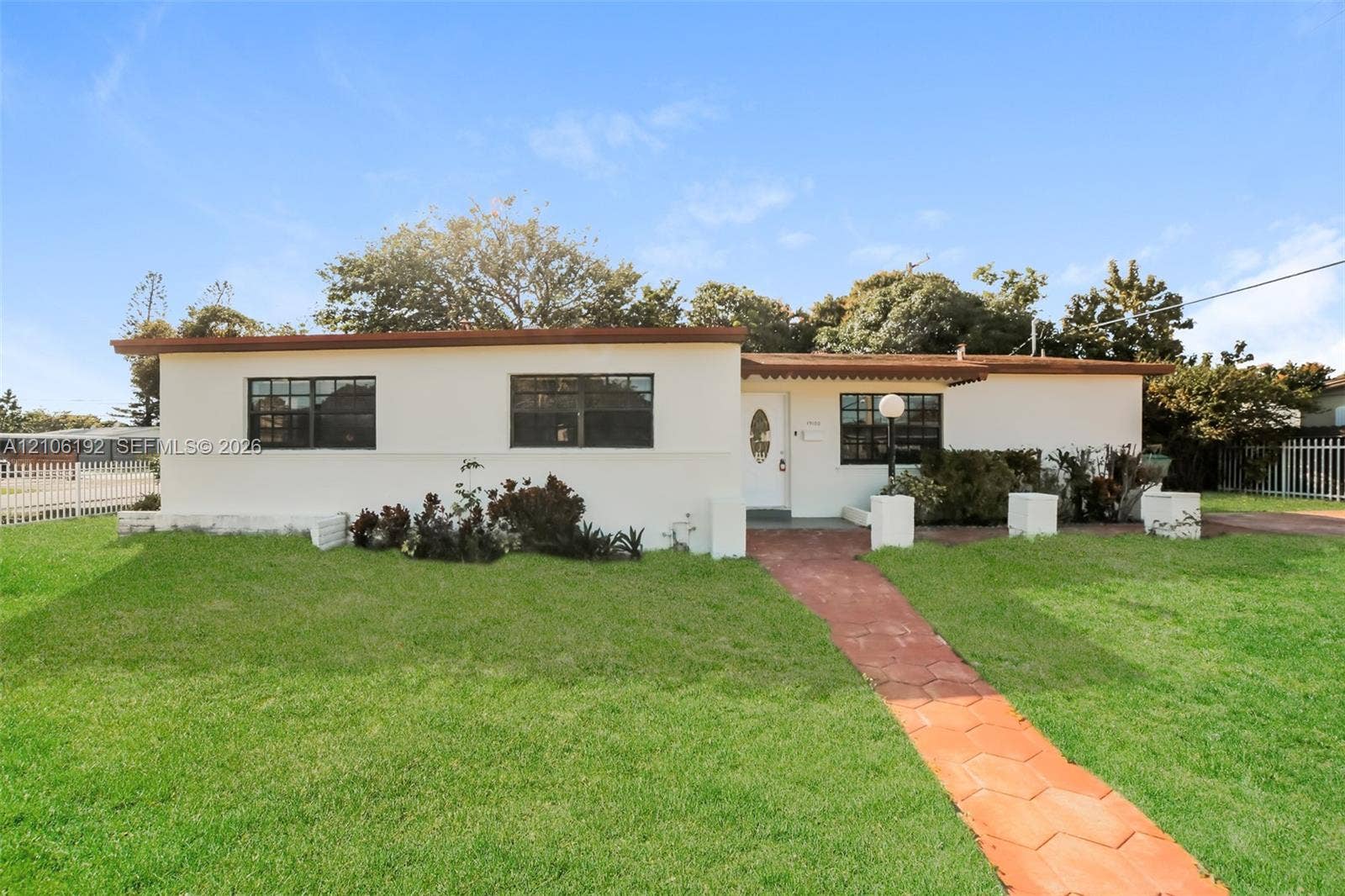19100 NW 12th Avenue, Miami Gardens, Miami Gardens, FL 33169 Single-story exterior featuring light-toned stucco siding, multi-pane windows, a central front entry, and a paved stone walkway