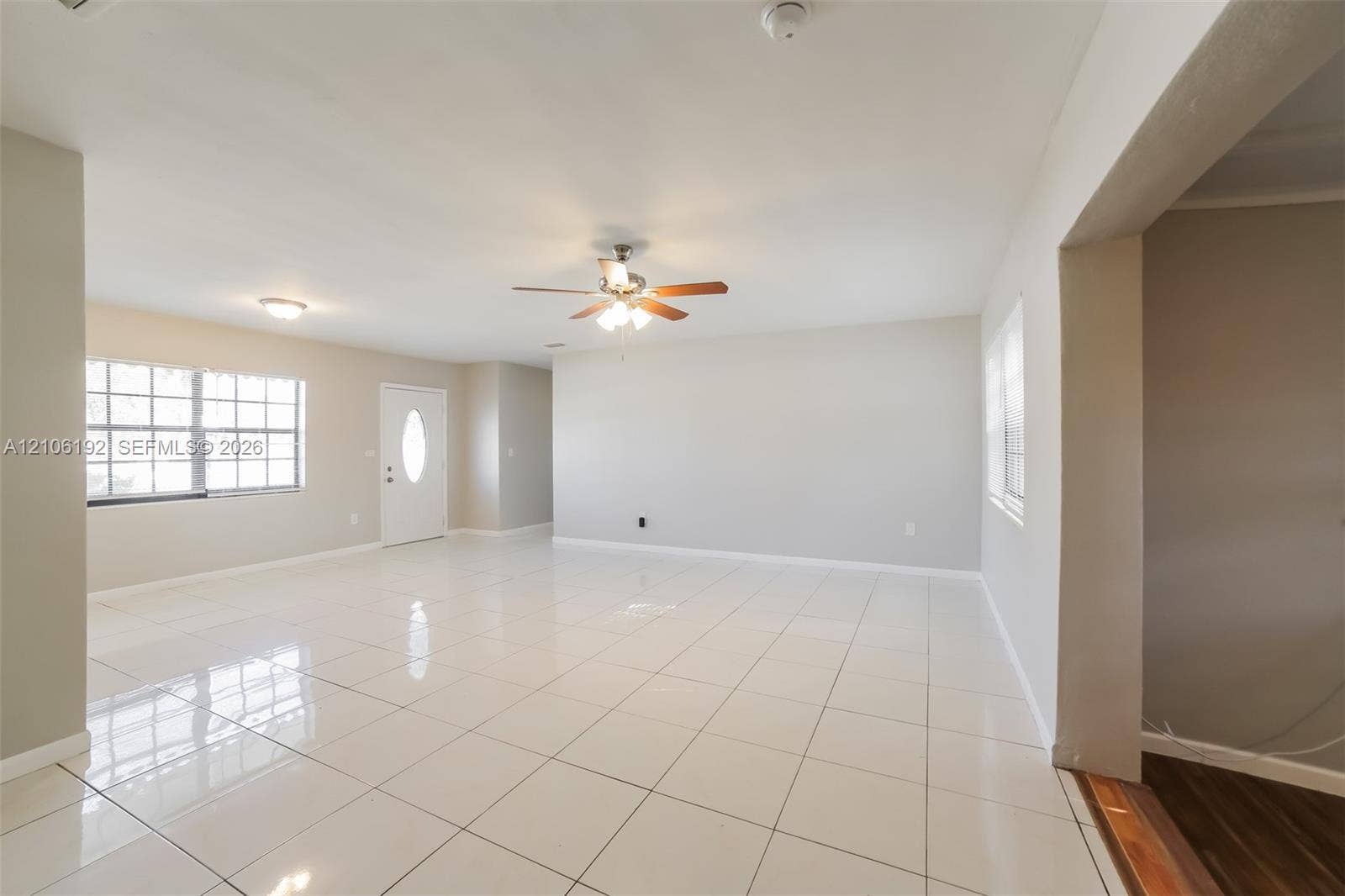 19100 NW 12th Avenue, Miami Gardens, Miami Gardens, FL 33169 Neutral interior featuring white ceramic tile flooring, a multi-blade ceiling fan with integrated lighting, and white-paneled entry door with an oval glass insert