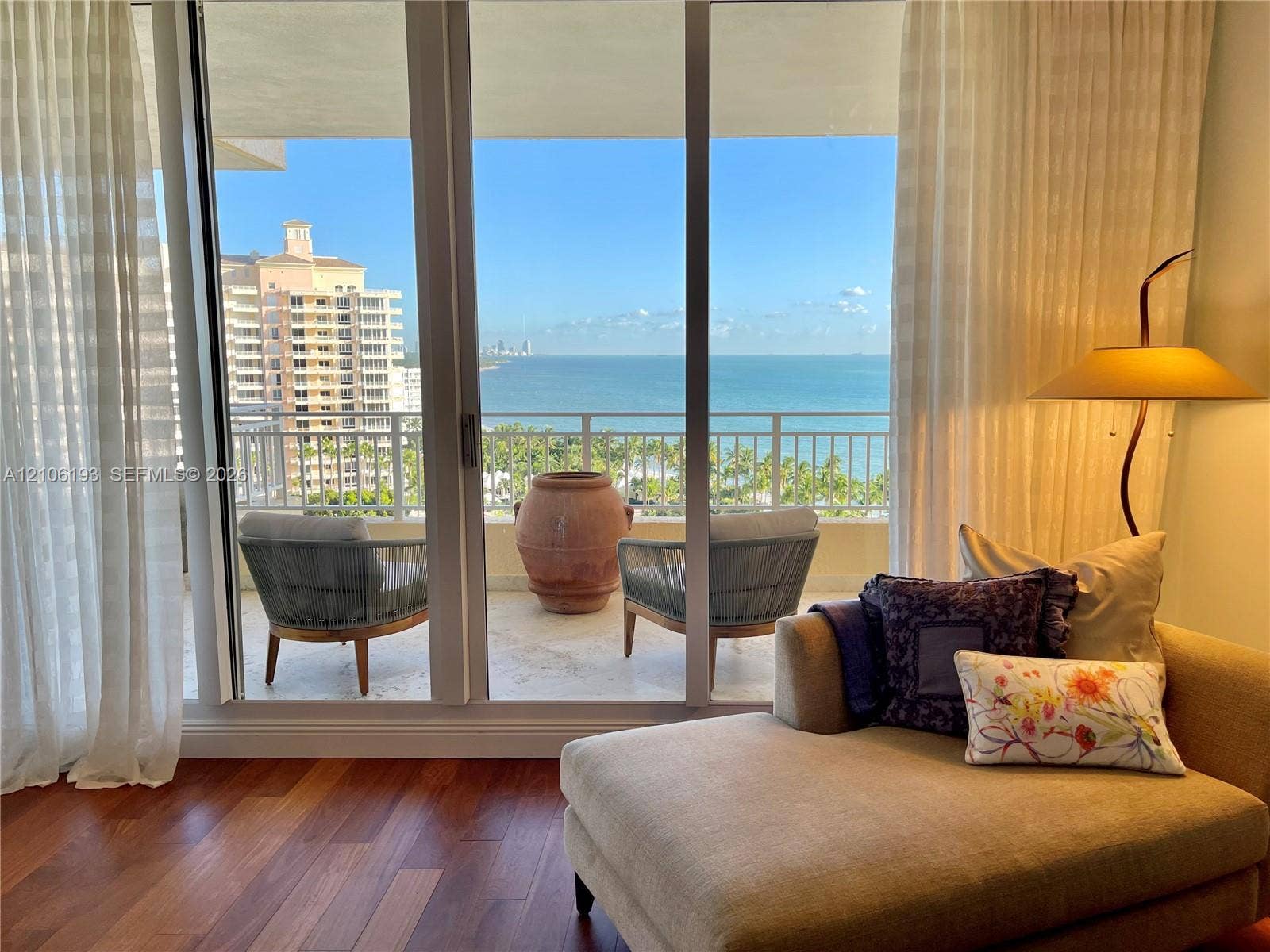 799 Crandon Boulevard, #1203, Key Biscayne, Key Biscayne, FL 33149 Floor-to-ceiling glass sliding doors, wood-finish flooring, and a stone-tiled balcony with metal railing