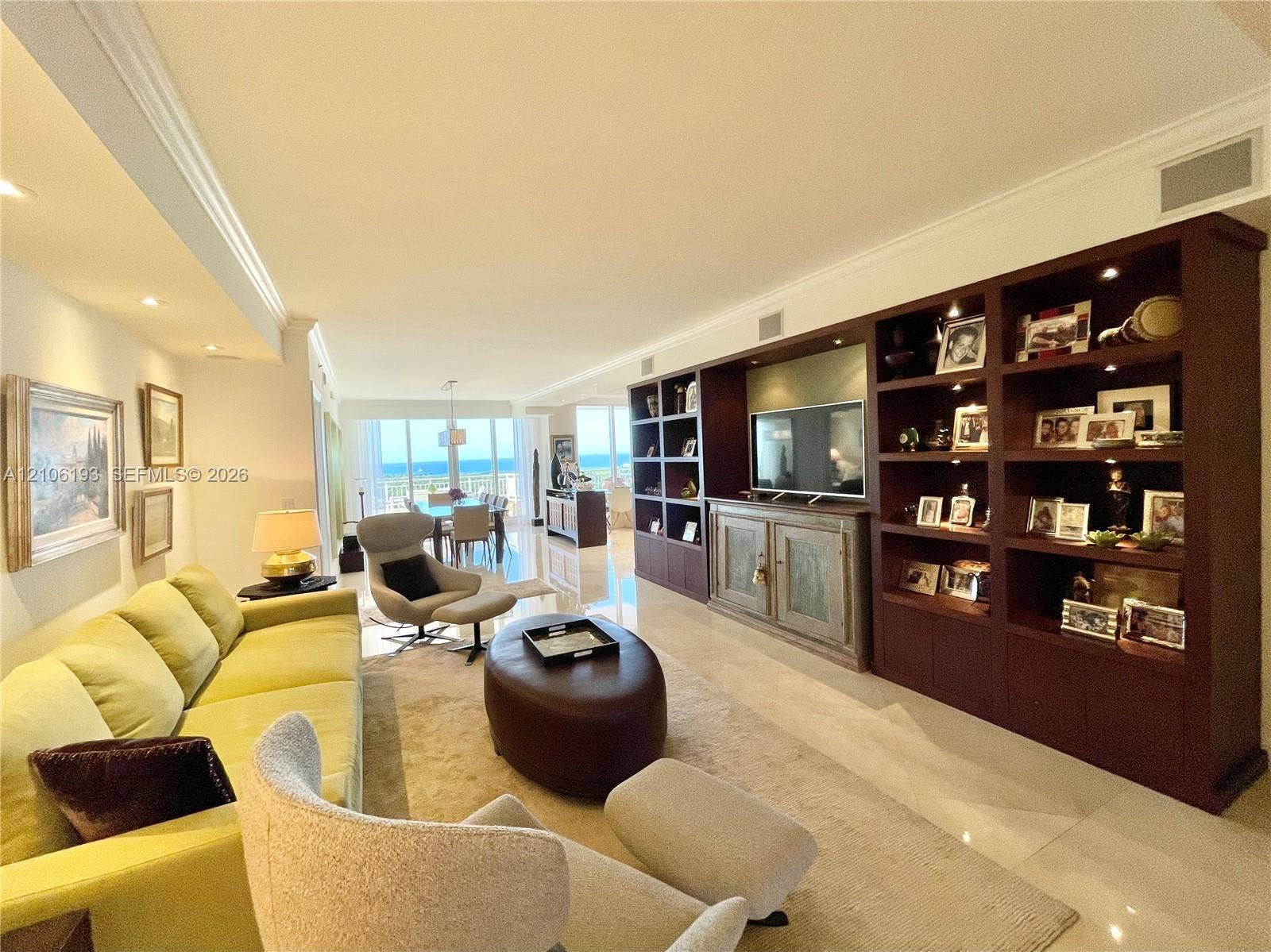 799 Crandon Boulevard, #1203, Key Biscayne, Key Biscayne, FL 33149 Large living area featuring polished stone flooring, extensive built-in floor-to-ceiling dark wood shelving, recessed lighting, and floor-to-ceiling windows