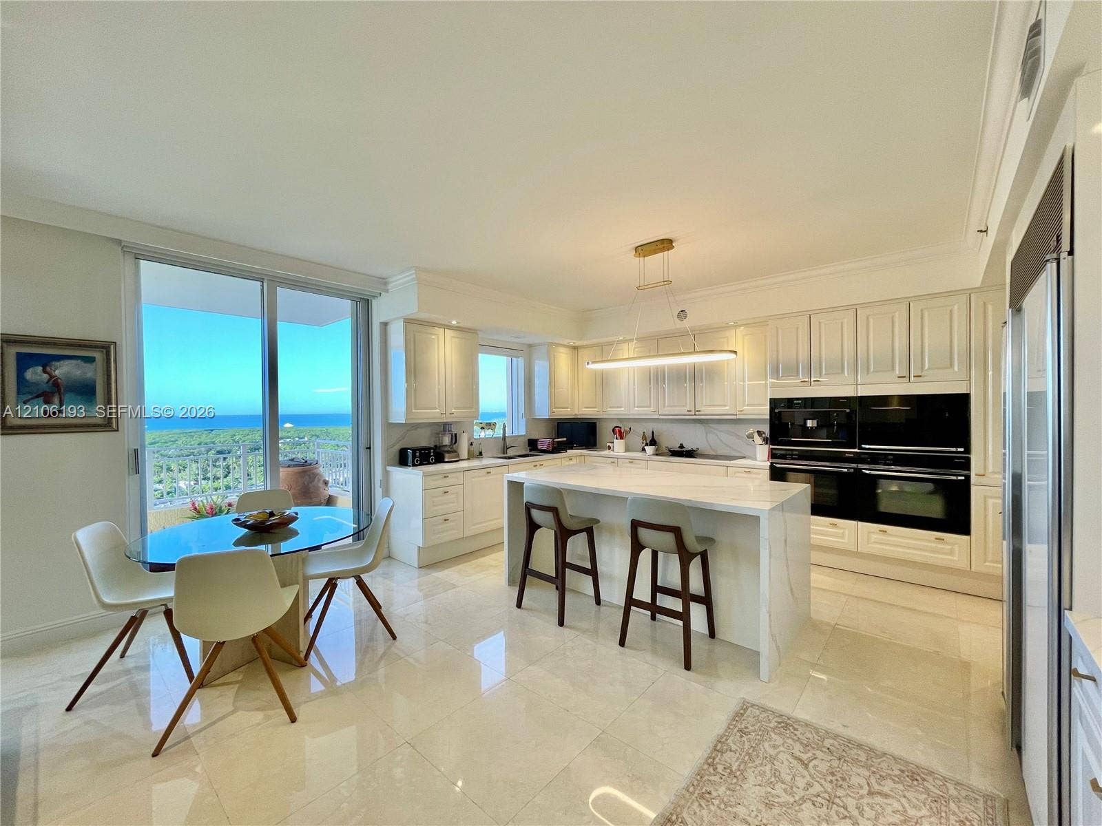 799 Crandon Boulevard, #1203, Key Biscayne, Key Biscayne, FL 33149 Kitchen featuring white cabinetry, an expansive center island with stone-finish countertops, built-in dual ovens, polished tile flooring, and sliding glass doors with ocean scenery