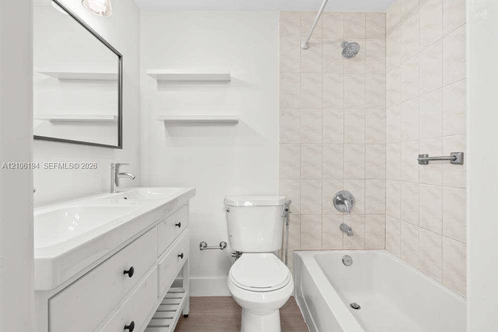 777 SW 9th Avenue, #408, Miami, FL 33130 Bathroom featuring a dual-sink vanity with matte black hardware, wall-mounted open shelving, a bathtub and shower combination with light-toned wall tile, and wood-finish flooring