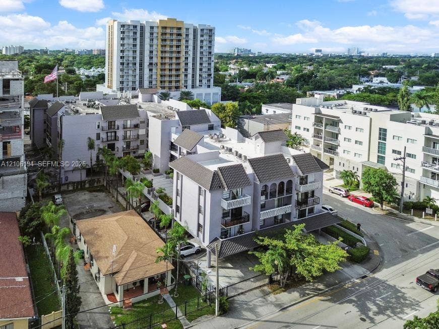 777 SW 9th Avenue, #408, Miami, FL 33130 Aerial perspective of a multi-story residential building featuring covered parking, gabled rooflines, decorative arched trim, and gated perimeter access