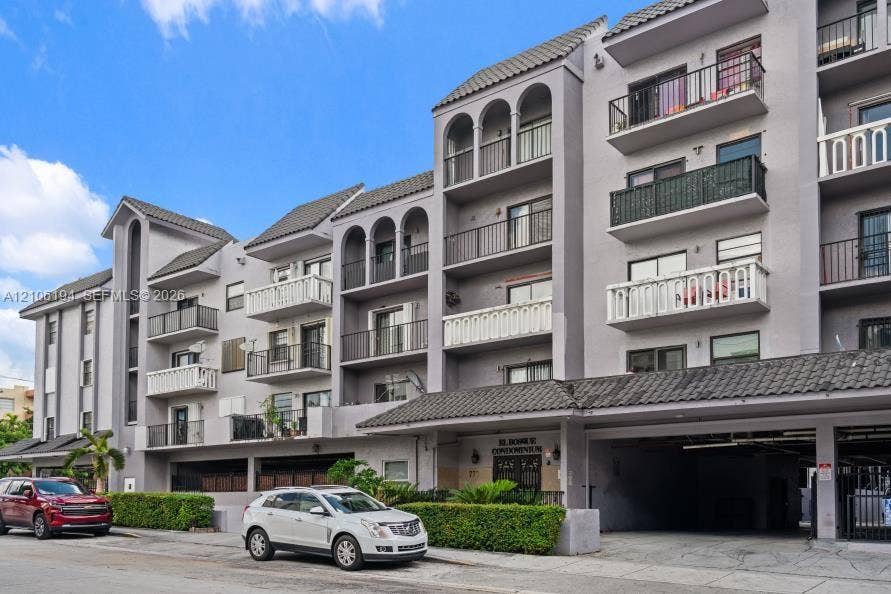 777 SW 9th Avenue, #408, Miami, FL 33130 Multi-story condominium exterior featuring arched architectural detailing, private balconies with metal railings, tile roof accents, and integrated covered parking
