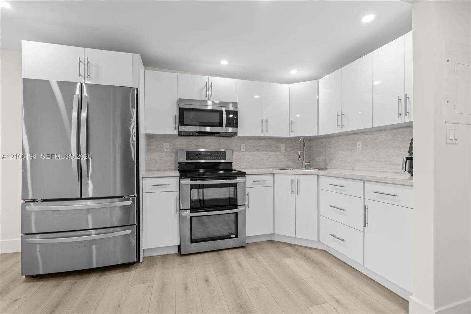 777 SW 9th Avenue, #408, Miami, FL 33130 Kitchen featuring white high-gloss cabinetry, stainless steel appliances, light-toned wood-finish flooring, and recessed lighting