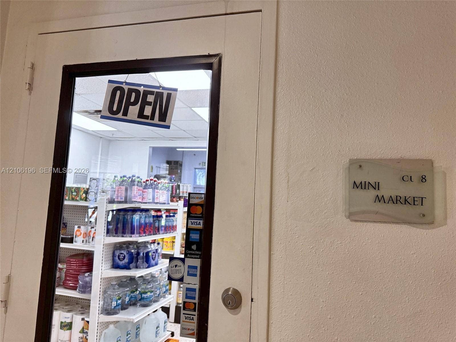 Commercial entrance featuring a glass-panel door with metal framing, a cylindrical deadbolt lock, and an integrated signage plaque
