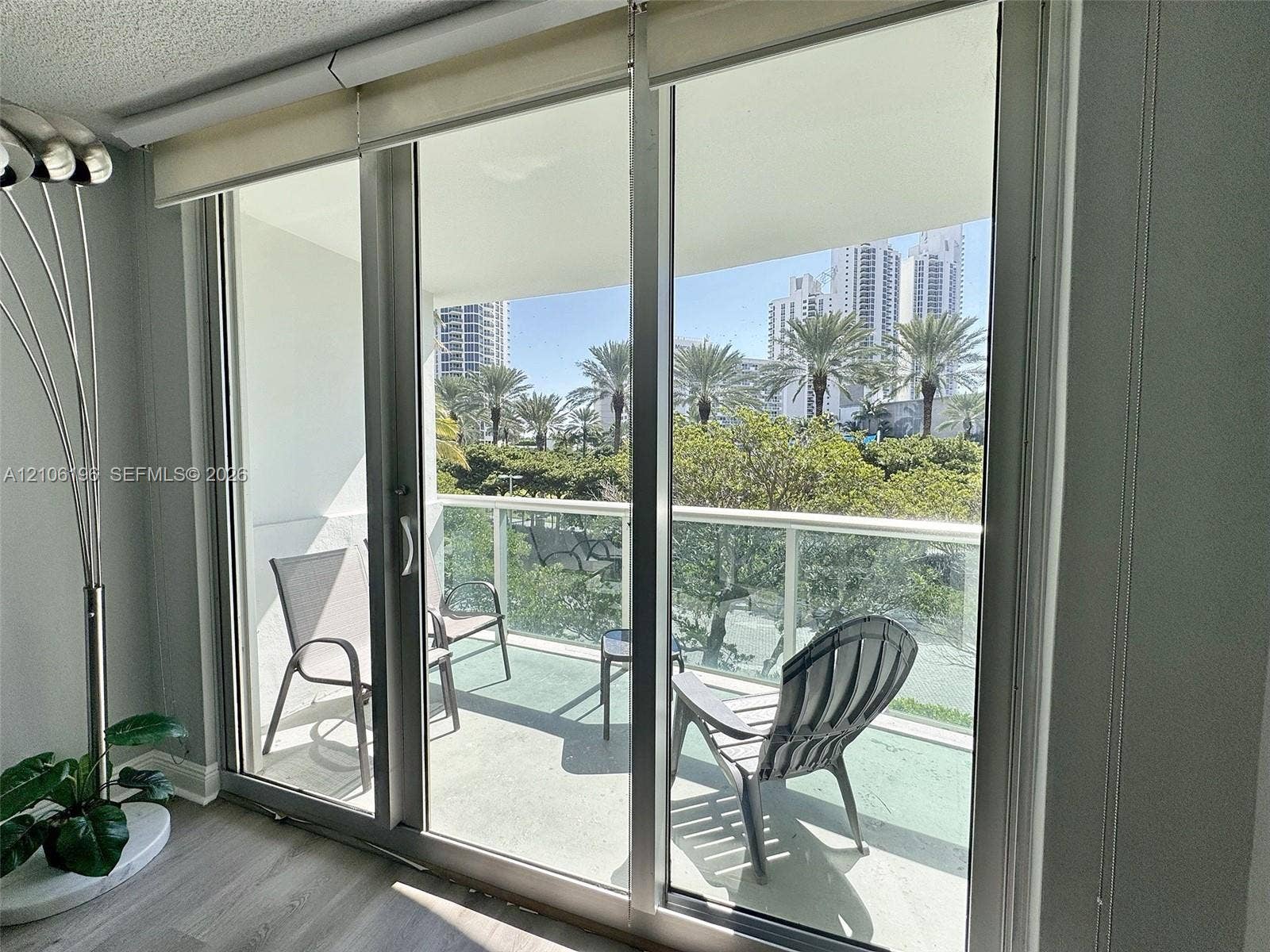Full-height sliding glass doors with aluminum frames opening to a balcony featuring a glass-paneled railing