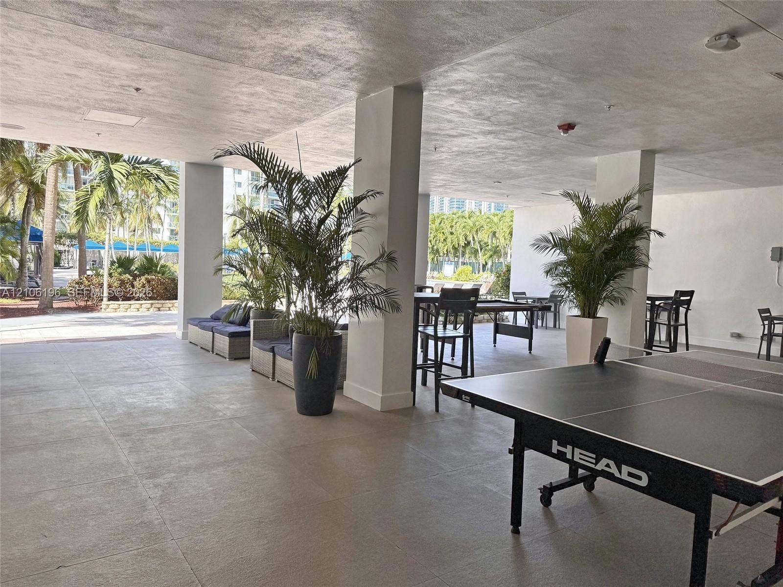 Covered outdoor recreational space featuring tile flooring, structural columns, and an open-air layout