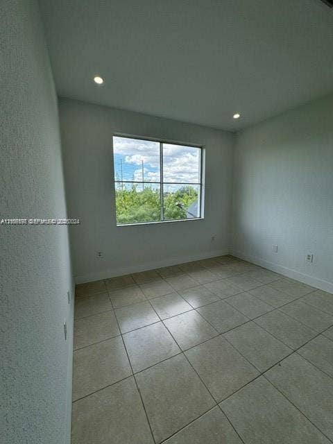 17660 NW 73rd Avenue, #202-3, Hialeah, Hialeah, FL 33015 Neutral-toned room featuring large-format tile flooring, recessed ceiling lighting, and a window with exterior greenery