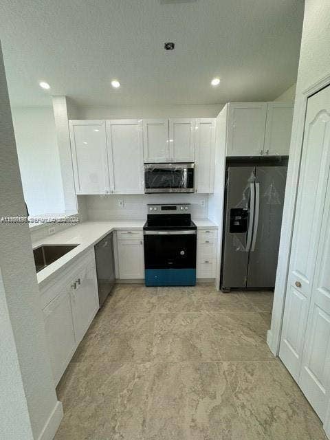 17660 NW 73rd Avenue, #202-3, Hialeah, Hialeah, FL 33015 Kitchen featuring white shaker-style cabinetry, solid-surface countertops, large-format tile flooring, stainless steel appliances, and a recessed sink