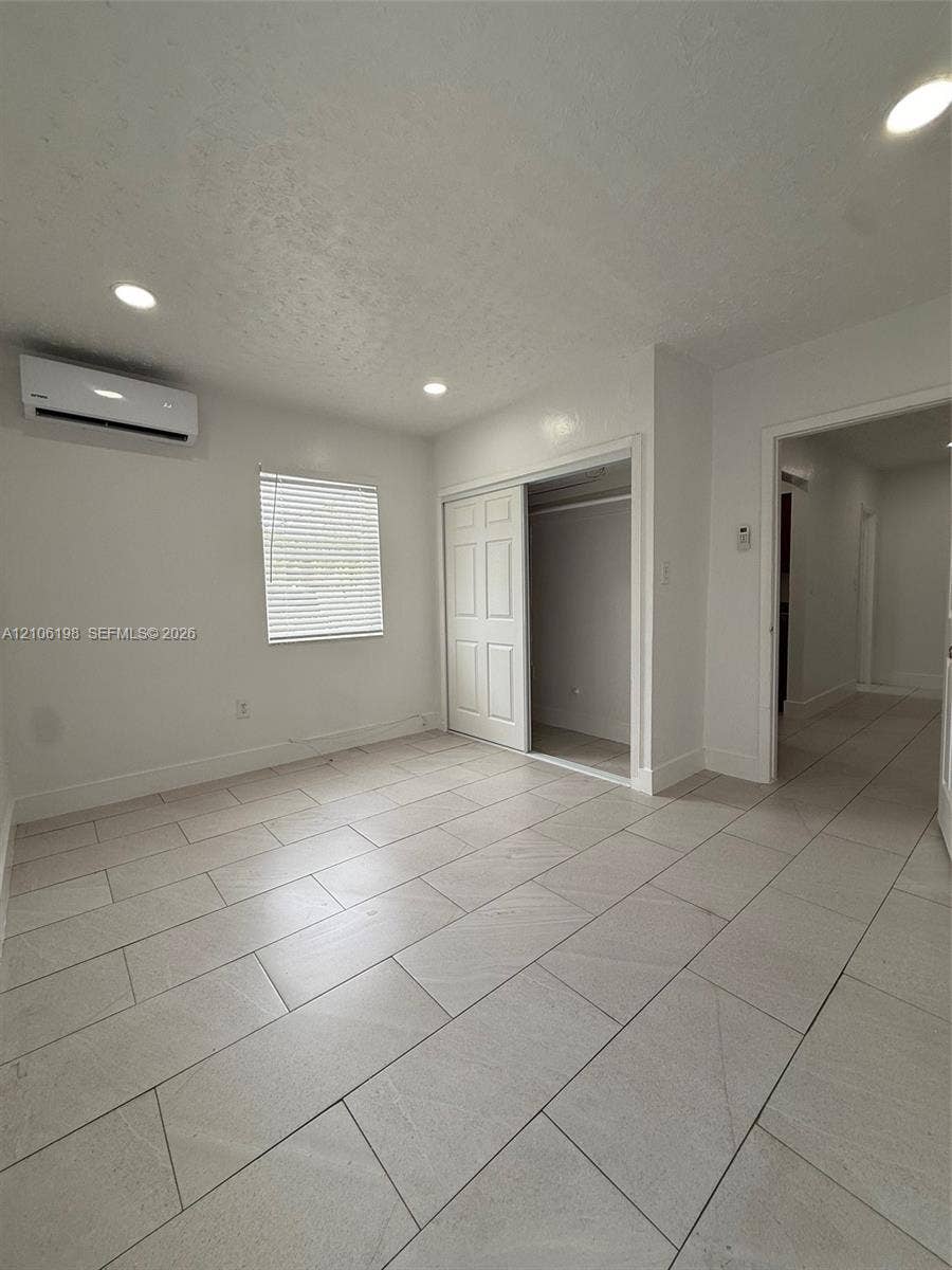 600 NW 116th Terrace, Miami, FL 33168 Neutral-toned tile flooring, recessed ceiling lighting, wall-mounted ductless climate control unit, and sliding closet doors