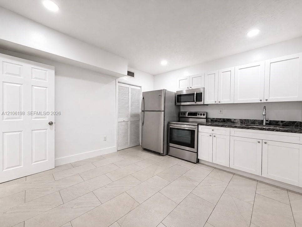600 NW 116th Terrace, Miami, FL 33168 Kitchen featuring white Shaker-style cabinetry, dark stone-finish countertops, stainless steel appliances, and tile flooring