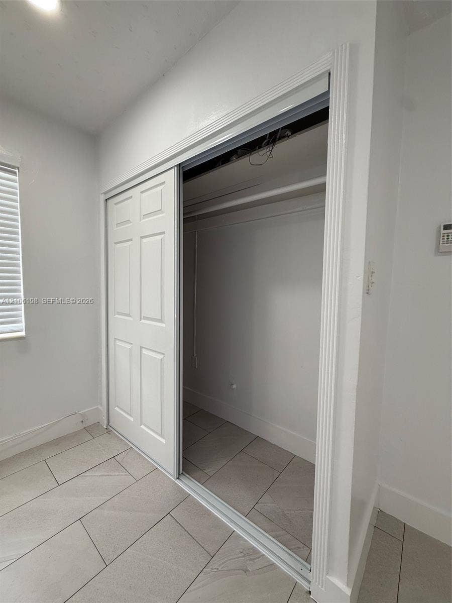 600 NW 116th Terrace, Miami, FL 33168 Closet featuring six-panel sliding doors, overhead rod, and large-format tile flooring