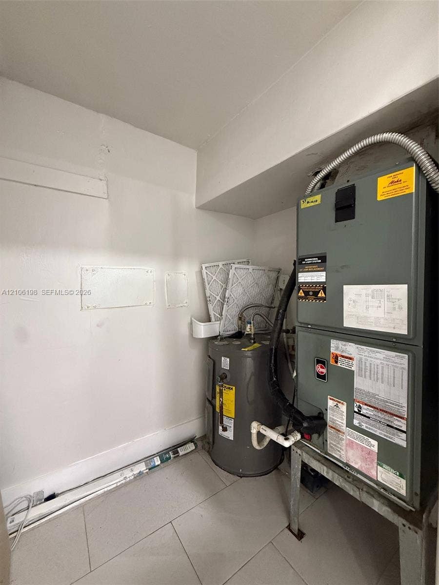 600 NW 116th Terrace, Miami, FL 33168 Utility closet containing a vertical HVAC unit and water heater, finished with tile flooring