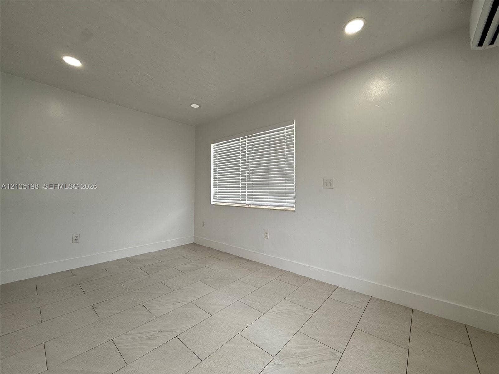 600 NW 116th Terrace, Miami, FL 33168 Neutral-toned interior room featuring large-format ceramic tile flooring, recessed ceiling lighting, and a window with horizontal blinds