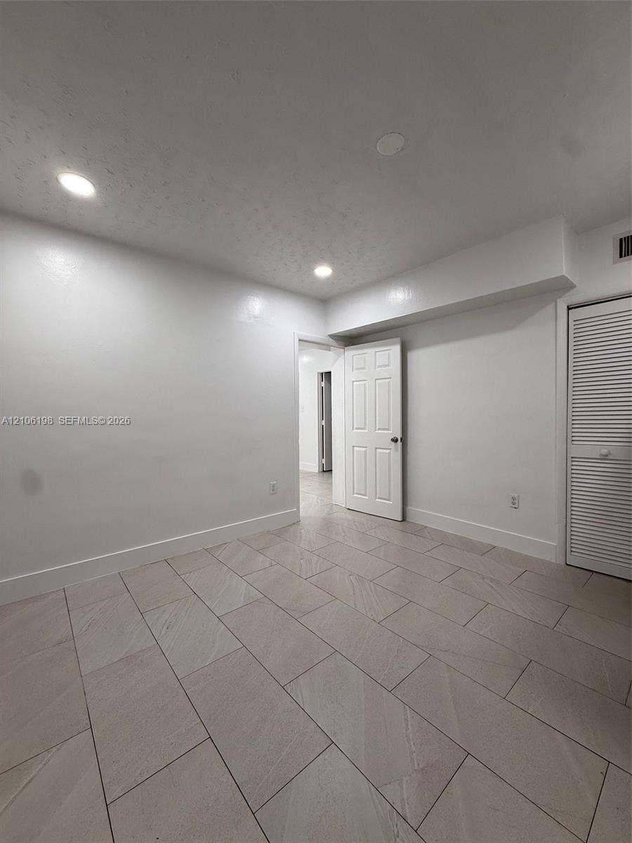 600 NW 116th Terrace, Miami, FL 33168 Neutral-toned tile flooring, recessed ceiling lighting, and six-panel interior door with louvered closet door
