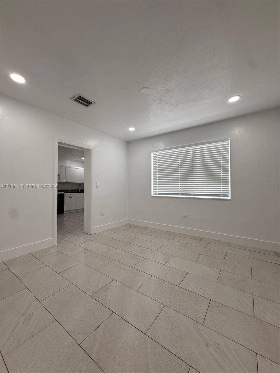 600 NW 116th Terrace, Miami, FL 33168 Interior space featuring neutral wall tones, large-format tile flooring, recessed ceiling lighting, and a window with horizontal blinds