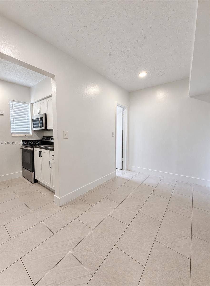 600 NW 116th Terrace, Miami, FL 33168 Neutral-toned large-format tile flooring, white cabinetry, integrated stainless steel appliances, and recessed lighting
